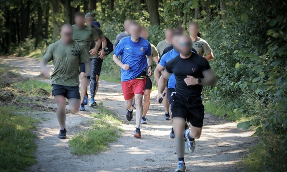 grupa mężczyzn biegnących leśną drogą