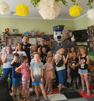 Policjanci, maskotka policyjna i grupa dzieci pozują do zdjęcia.