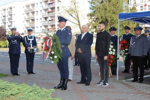 ojciec zmarłego policjanta wraz z wnukami składa wieniec pod obeliskiem