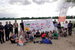 Policjanci i uczestnicy imprezy pozują do zdjęcia na plaży.