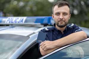 St. sierż. Dominik Napierała przed Komisariatem Policji w Puszczykowie, przy radiowozie