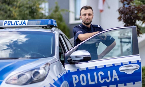 St. sierż. Dominik Napierała przed Komisariatem Policji w Puszczykowie, przy radiowozie