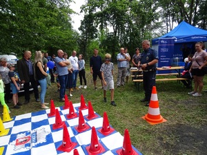 Policjant i uczestnicy pikniku w tle namiot profilaktyczny Policji.