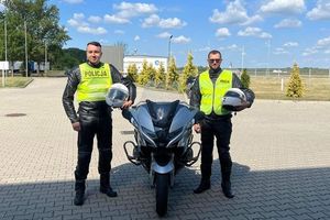 dwaj policjanci stoją przy motocyklu