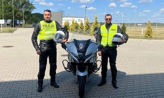 dwaj policjanci stoją przy motocyklu