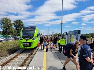 uczestnicy festiwalu wysiadający z pociągu  na peronie dworca kolejowego i policjant