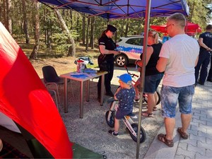 Policjantka w namiocie profilaktycznym Policji z uczestnikami spotkania.