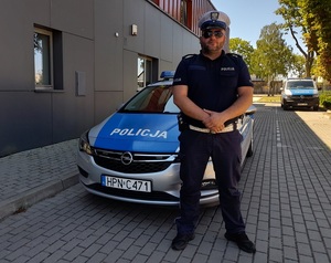 policjant ruchu drogowego stoi przed radiowozem