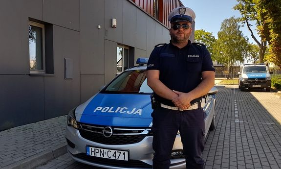 policjant ruchu drogowego stoi przed radiowozem