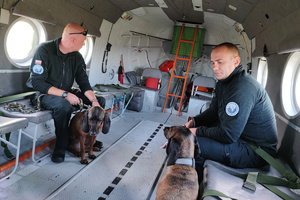 Dwaj policjanci z psami służbowymi na pokładzie śmigłowca.