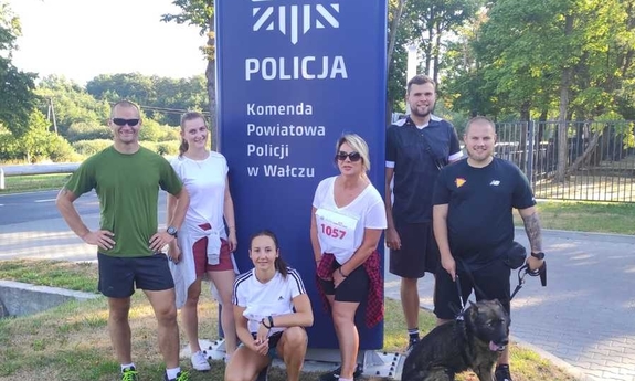 wspólne zdjęcie uczestników biegu, w tle logo policji