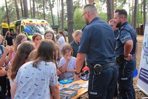 Policjanci rozdają dzieciom gadżety profilaktyczne promujące bezpieczne zachowania.