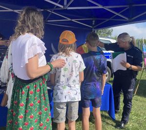 Policjantka i dwoje dzieci wraz  z opiekunem grają w grę plenerową.