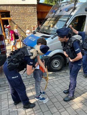 dwie policjantki stoją przy odnalezionym chłopcu, w tle radiowóz