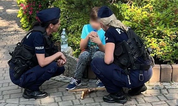 dwie policjantki kucają przy odnalezionym chłopcu