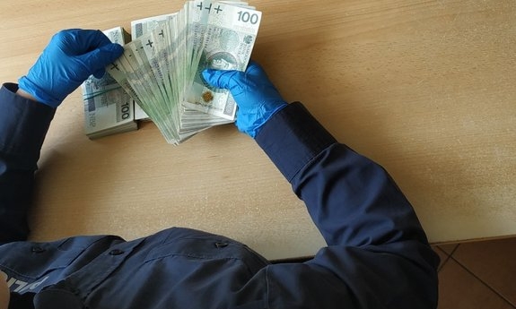 policjant liczy zabezpieczone pieniądze