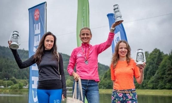 trzy kobiety stojące na podium zawodów sportowych