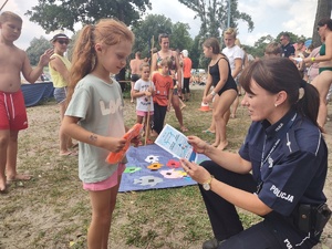 Policjantka z dziećmi grającymi w grę plenerową.