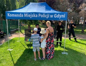 Policjantka i strażacy rozmawiają z uczestnikami imprezy.