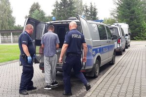 policjanci z zatrzymanym przy radiowozie