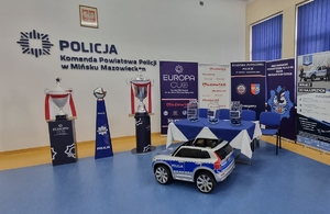 trzy trofea stoją przy ścianie z napisem Komenda Powiatowa policji w Mińsku Mazowieckim