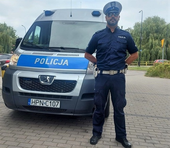 policjant stoi przy radiowozie