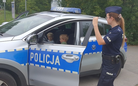 policjantka pilnuje dzieci siedzące w samochodzie