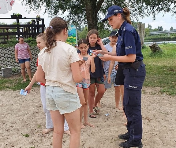 policjantka rozdaje ulotki dzieciom