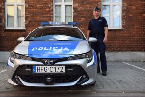 umundurowany policjant stoi przy radiowozie