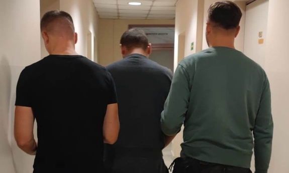 policjanci prowadzą zatrzymanego mężczyznę podejrzanego o zabójstwo