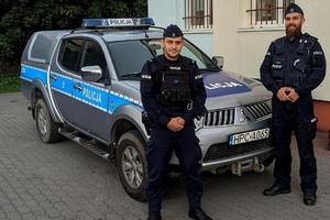 Dwaj policjanci stoją przy radiowozie