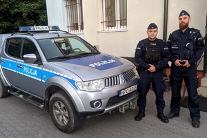 Dwaj policjanci stoją przy radiowozie