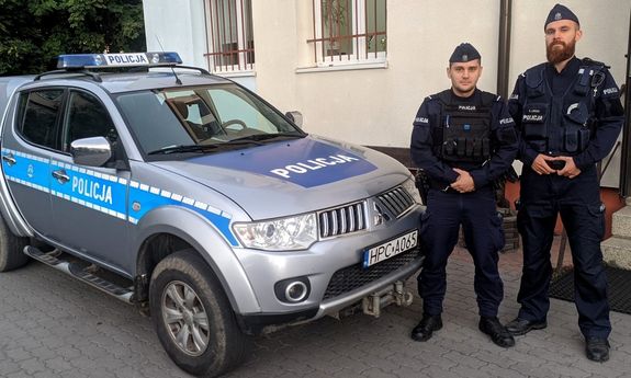 Dwaj policjanci stoją przy radiowozie