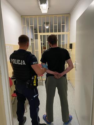 umundurowany policjant prowadzi zatrzymanego mężczyznę