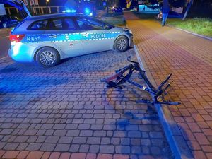na zdjęciu rower leży na ulicy, w tle stoi radiowóz