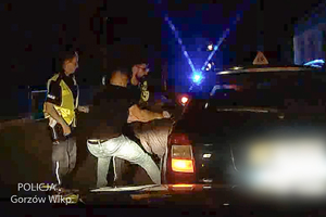 pora nocna - dwoje policjantów w żółtych kamizelkach i policjant po cywilnemu wyciągają z auta mężczyznę