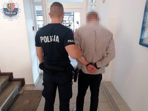 policjant z zatrzymanym mężczyzną zakutym w kajdanki