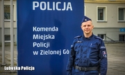 Policjant na tle logo Komendy Miejskiej Policji w Zielonej Górze