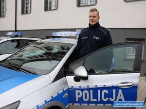 policjant stojący koło radiowozu