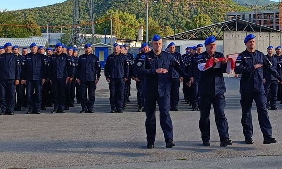 nowo przybyli na rotację funkcjonariusze stoją na placu apelowym. Z boku poczet sztandarowy z flagą Polski