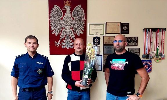 mężczyzna dziękuje policjantowi za okazaną pomoc wręczając kwiaty