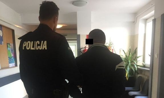 Policjant prowadzi zatrzymanego mężczyznę