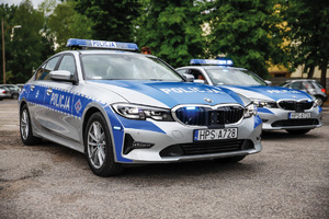 na zdjęciu dwa radiowozy marki bmw 320i stoją obok siebie na parkingu