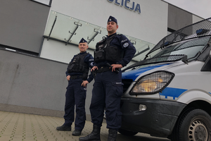 Funkcjonariusze Oddziału Prewencji Policji w Krakowie stoją przed radiowozem Mercedes-Sprinter. W tle jednostka policji