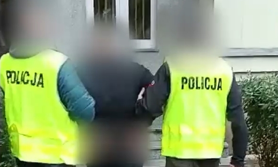 dwaj policjanci prowadzą zatrzymanego mężczyznę