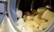 biała substancja w formie bryłek w bębnie otwartej pralki automatycznej