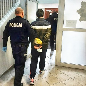 policjant prowadzi zatrzymanego