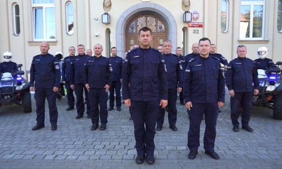 grupa policjantów stoi przed budynkiem