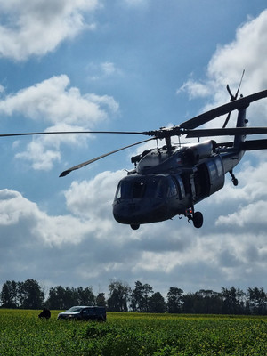 Policyjny helikopter nadlatuje nad samochód terenowy.