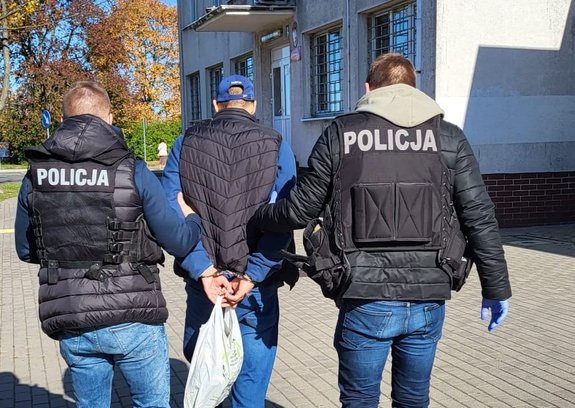 Dwaj policjanci prowadzą zatrzymanego